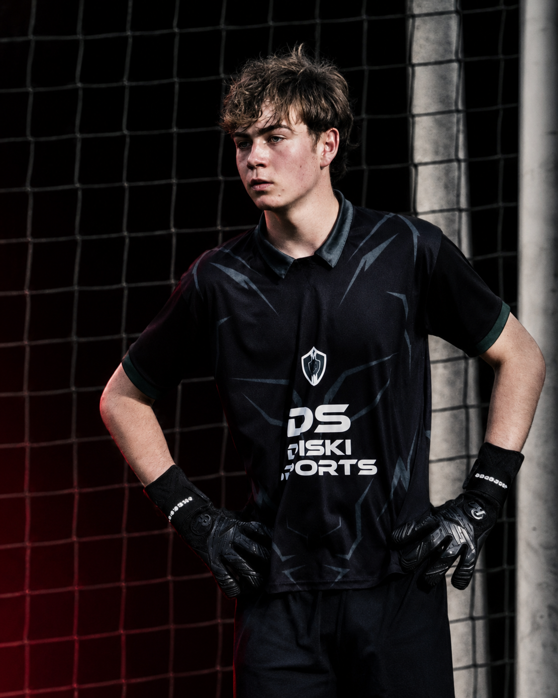 Jason Finlay standing thoughtfully in front of a football goal wearing goalkeeper gloves.