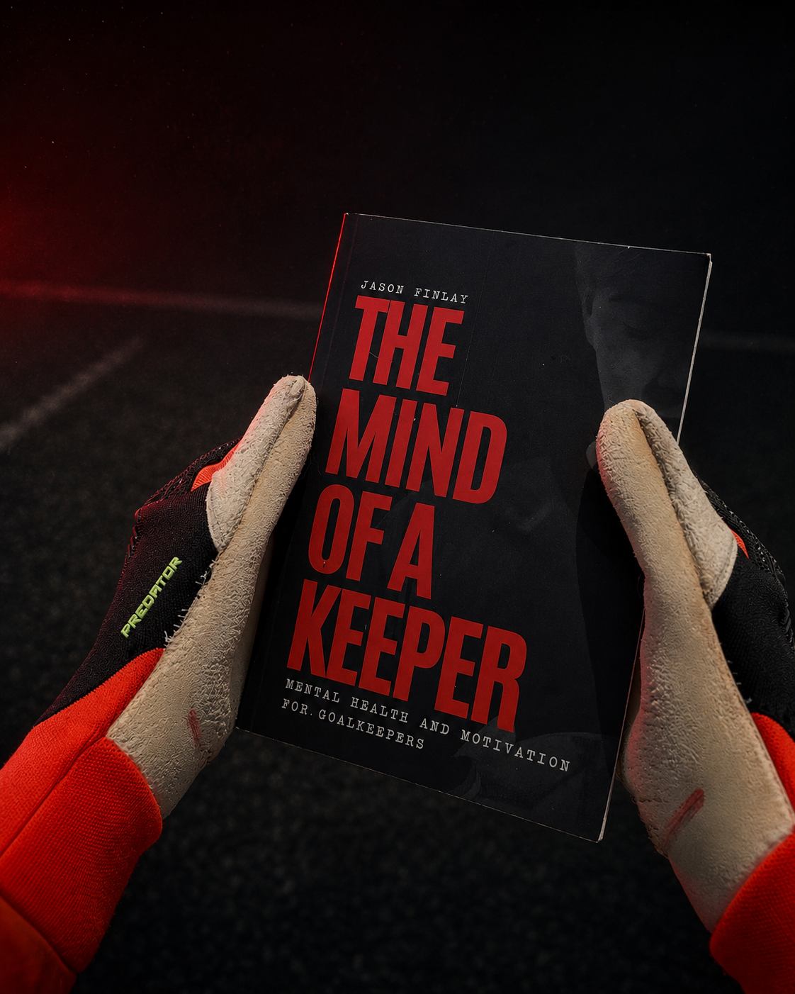 Goalkeeper gloves holding Jason Finlay's book The Mind of a Keeper.